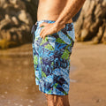 Side view of men’s tropical leaf print swim shorts at the beach, relaxed fit boardshorts for swimming and surfing